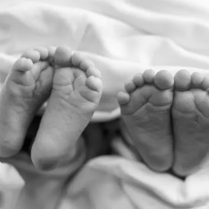 The feet of two newborns resting on a white blanket.