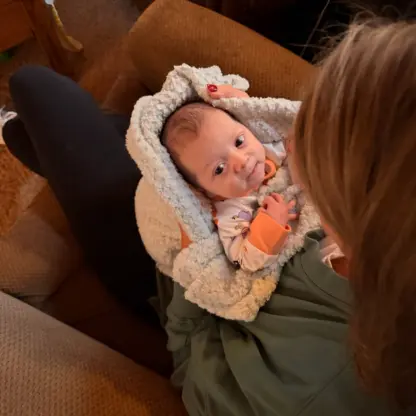 A person holding a baby wrapped in a light blue textured blanket.