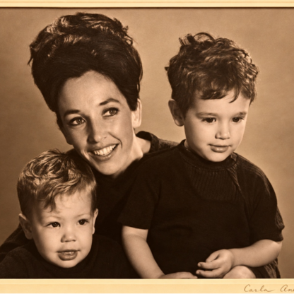 Sepia-toned studio portrait of a smiling woman with two young boys.