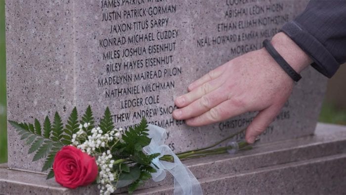 Hand touching a funeral headstone.