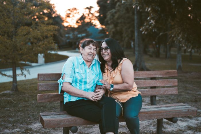 Mother and daughter laugh on park bench