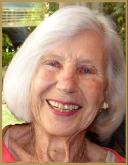 a woman, with tinted lipstick and silver hair cut in a bob, smiles brightly