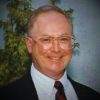 portrait of a smiling man in a suit and glasses