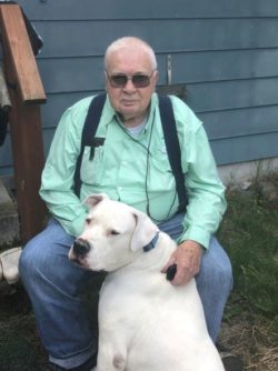 a man sitting down with a dog at his feet