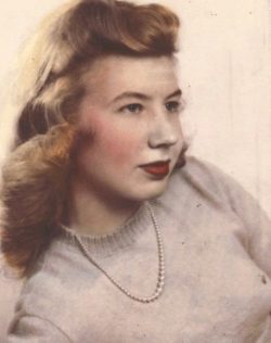 a woman looking off in the distance wearing a sweater and pearls