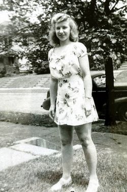 a woman smiling in a summer dress on a front lawn