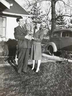 a young family and their baby posing outside a home