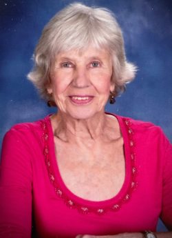 a woman, with tinted lipstick and silver hair cut in a bob, smiles brightly