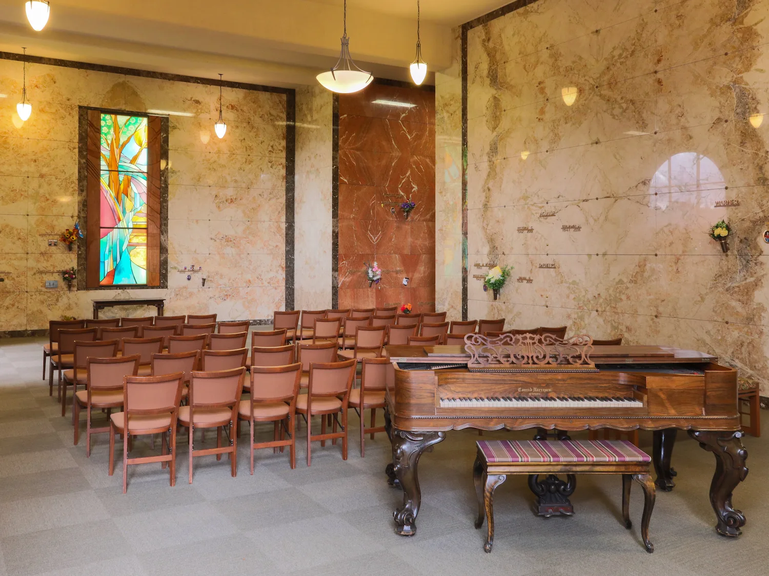 Marble mausoleum with beautiful wooden piano, chairs, and colorful stained glass window