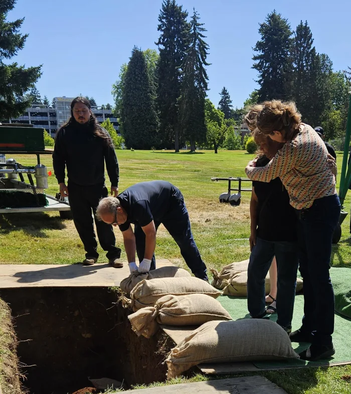 Four people stand near an open grave at BONNEY WATSON Washington Memorial Park